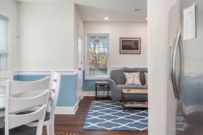 A compact living space with a dining area, a sofa, and a refrigerator. - Beautiful Renovated Townhome w/parking (Holden)