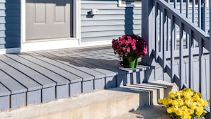 A blue house with a gray door, a small porch with steps, and two flower pots with flowers. - Beautiful Renovated Townhome w/parking (Holden)