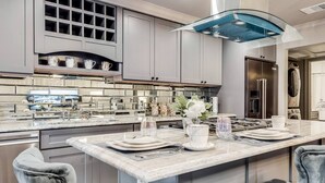 A modern kitchen with grey cabinetry, a marble countertop, and a central island with seating. - Spacious 1-Bedroom Dallas condo minutes from downtown, designed to Marriott Gold Standards and featuring the Pod Pro smart bed for peak comfort (Dallas)