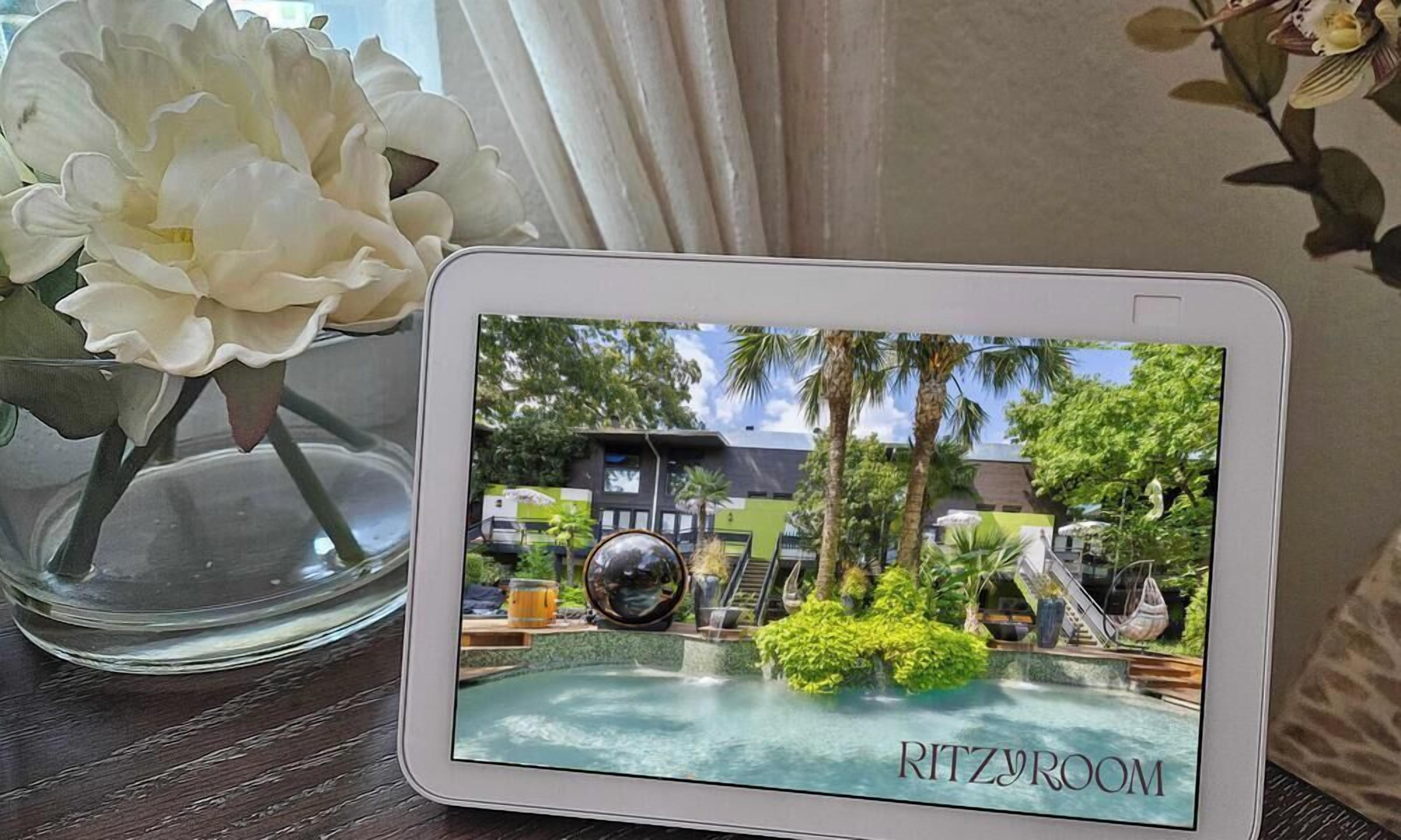 Una tableta muestra una escena de resort con piscina, palmeras y un edificio identificado como 'RITZROOM'.