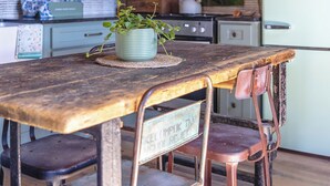Una cucina rustica con un tavolo di legno, sedie in metallo e un frigorifero d'epoca.