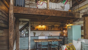Interno rustico di una baita con zona pranzo, angolo cottura e accogliente soggiorno.