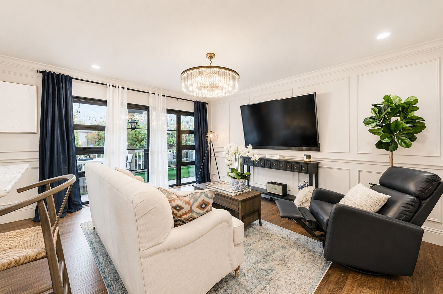 A living room with a sofa, armchair, TV, and a plant.