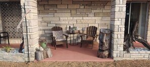 Relax in style with comfortable Adirondack chairs and a small table, set amidst a serene outdoor space.