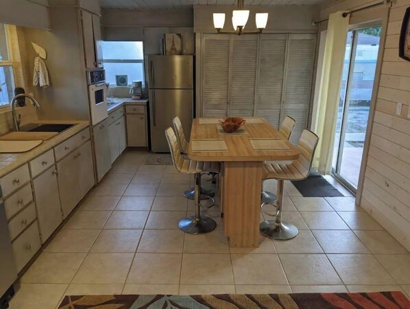 Enjoy meals in this kitchen with a central island, sink, oven, and refrigerator. Dine at the table with four chairs and take in the view through the sliding glass door.