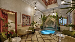 Una habitación lujosa con suelo de baldosas, una piscina pequeña y muebles ornamentados.