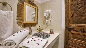 Un baño con lavamanos, espejo, secador de pelo, toalla y objetos decorativos.