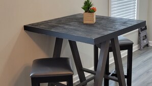 Un comedor con una mesa de madera oscura y un banco a juego, una planta en maceta sobre la mesa, y una pared con varios espejos redondos.