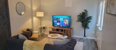 A living room with a sofa, a coffee table, a TV, a lamp, and a potted plant.