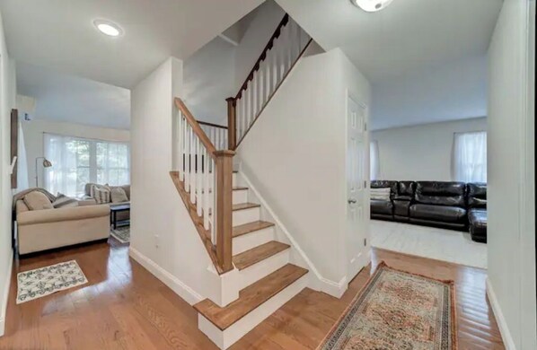 Cozy living area with a staircase leading to an upper floor, featuring a beige sofa and a black leather couch.