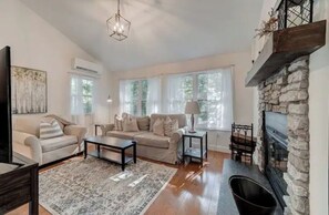 Relax in this inviting living room with a comfortable sofa, fireplace, and large windows offering a view of the outdoors.