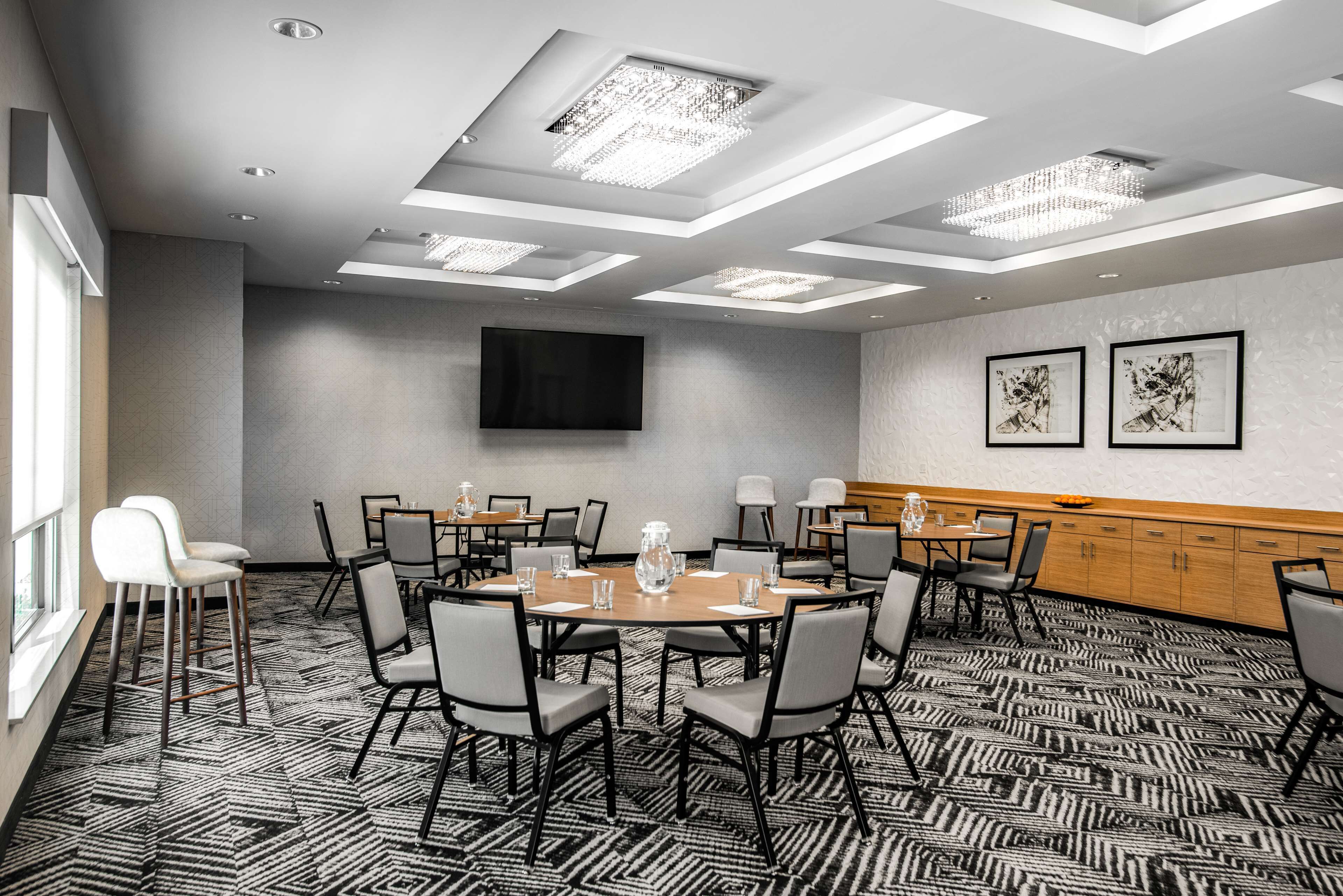 A conference room with a large table, chairs, a TV, and artwork on the walls.