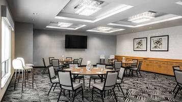 A conference room with a large table, chairs, a TV, and artwork on the walls.