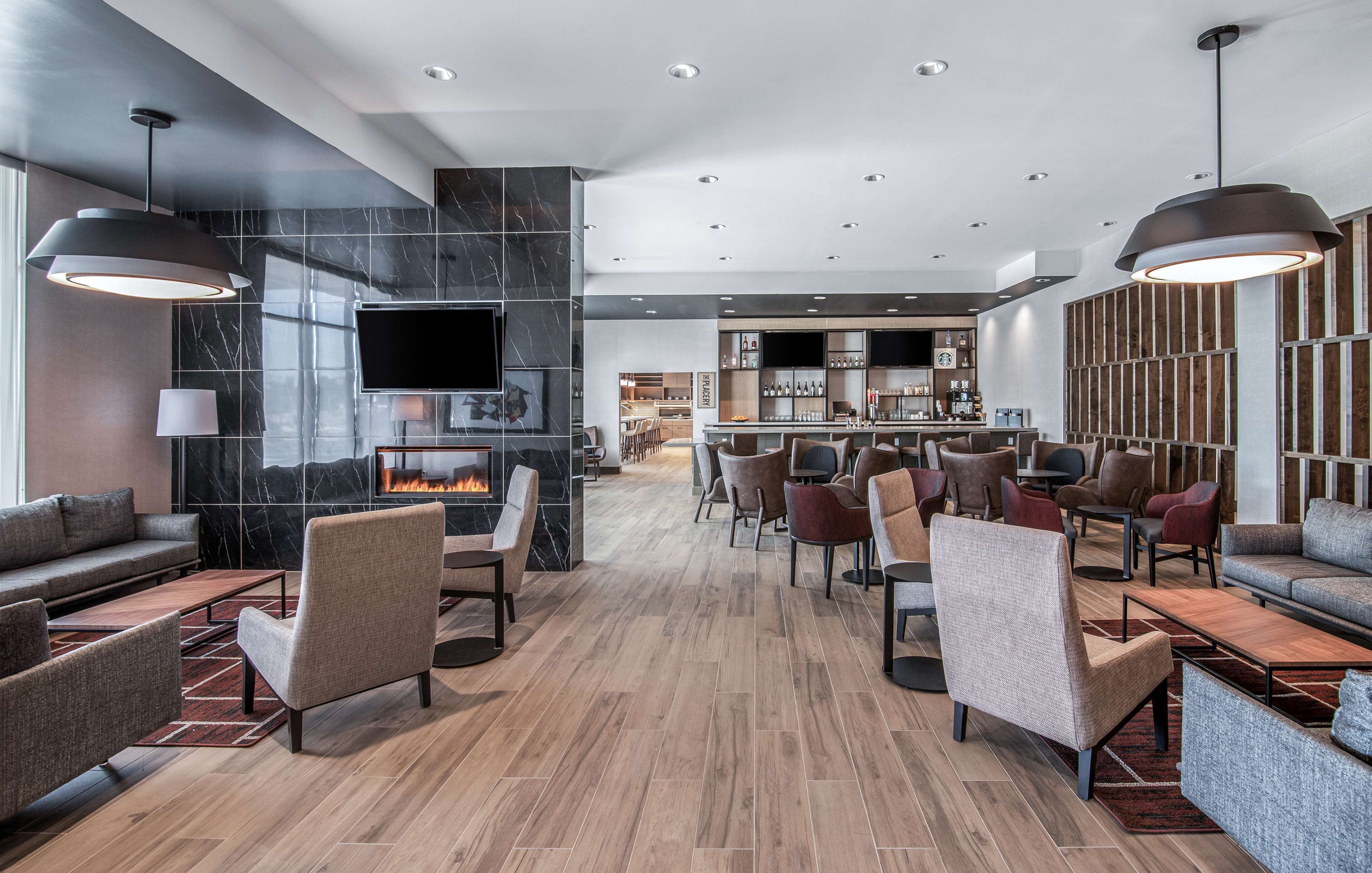 A modern lounge area with sofas, chairs, a fireplace, a TV, and a bar area.
