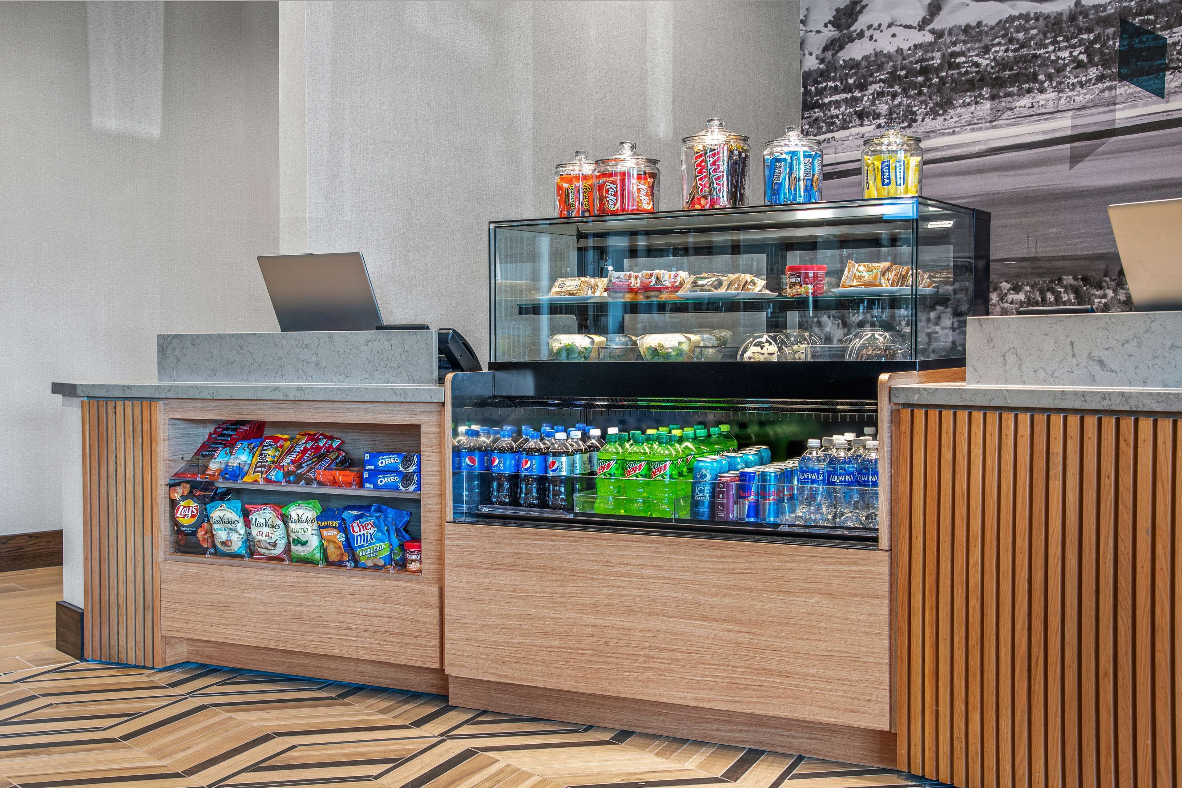A hotel reception area with a counter displaying snacks, bottled water, and a laptop.
