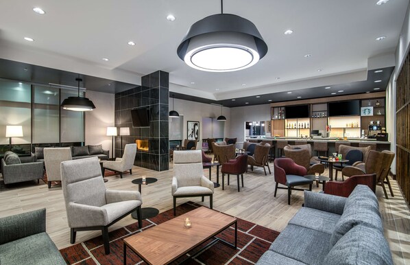 A modern lounge area with sofas, armchairs, and a bar with various beverages. - Hyatt Place Newark/Silicon Valley (Newark)