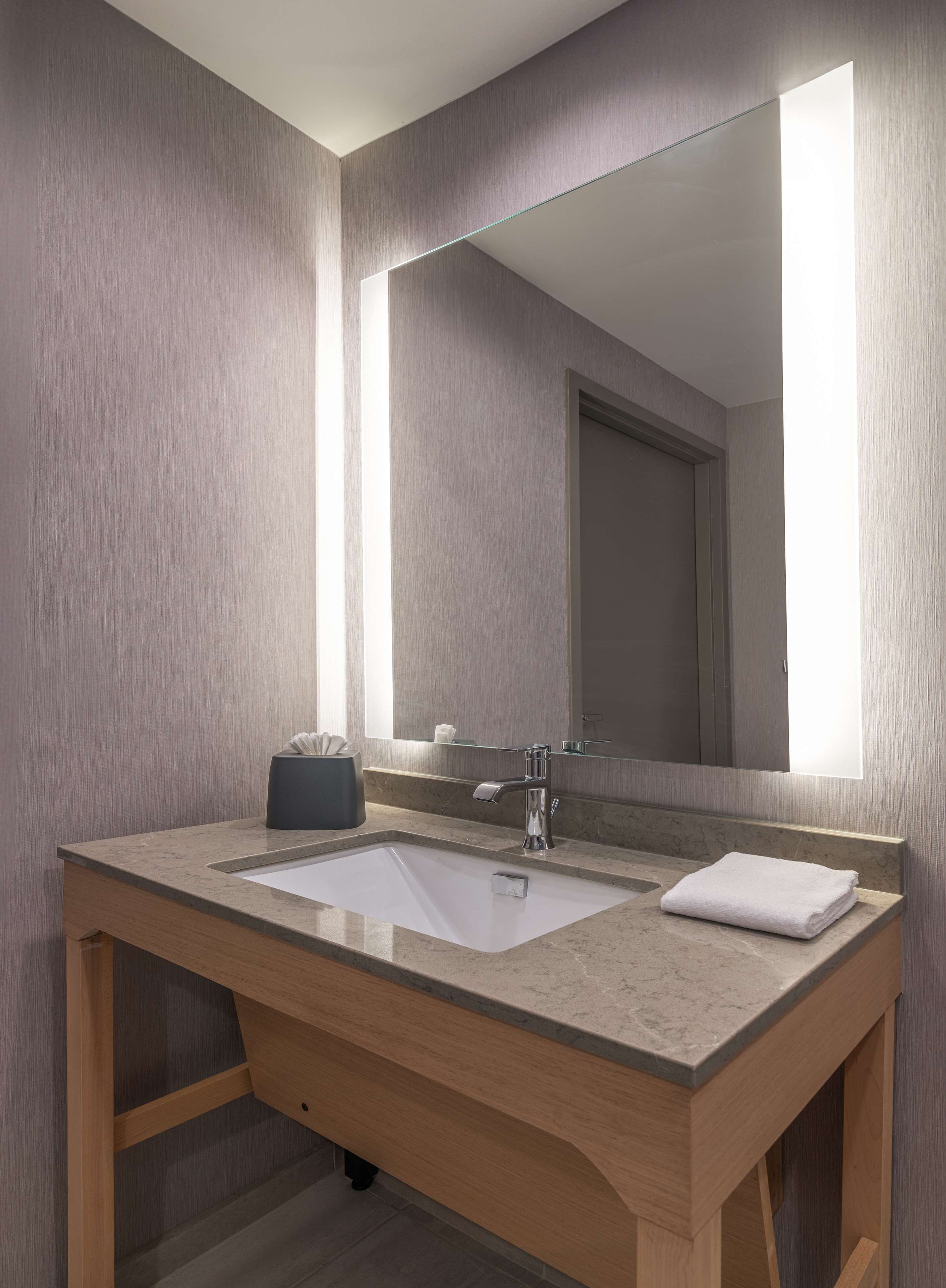 A bathroom with a large mirror, a sink, and a towel.