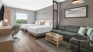 Ein modernes Hotelzimmer mit Bett, einer Couch, einem Schreibtisch und einem großen Fenster.
