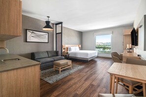 A modern hotel room with a bed, sofa, dining table, and kitchenette. - Hyatt Place Newark/Silicon Valley (Newark)