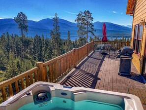 A wooden deck with a hot tub, outdoor furniture, and a view of mountains and trees. - Sleeps 16| Private Hot Tub, Game Room & Panoramic Views! (Grand Lake)