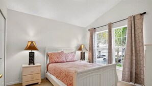 A bedroom with a bed, bedside lamps, a nightstand, a window with curtains, and a view of the outside. - South facing pool home with hot tub and games room - gated community (Davenport)