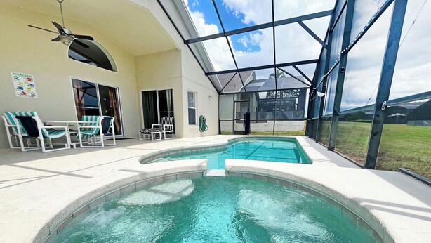A swimming pool with a glass enclosure, lounge chairs, and a ceiling fan. - South facing pool home with hot tub and games room - gated community (Davenport)