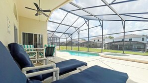A covered outdoor area with lounge chairs, a pool, and a view of neighboring houses. - South facing pool home with hot tub and games room - gated community (Davenport)