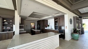 A modern kitchen with a central island, dark cabinetry, and a clock on the wall.