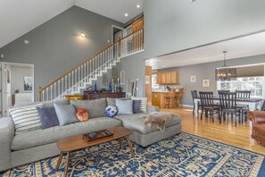 Relax in this stylish living area with a large sectional sofa, wooden coffee table, and staircase leading to an upper level.