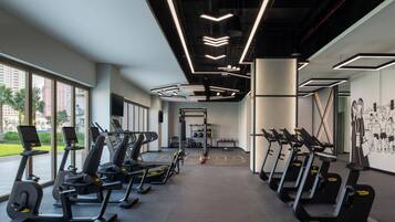 A gym with multiple treadmills, a weightlifting area, and large windows offering views of the outdoors.