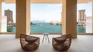 A balcony with two wicker chairs and a small table, overlooking a marina with boats and buildings. - The St. Regis Marsa Arabia Island, The Pearl Qatar (Doha)
