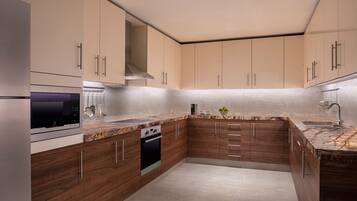 Una cocina moderna con armarios de madera, horno empotrado y encimera de granito.