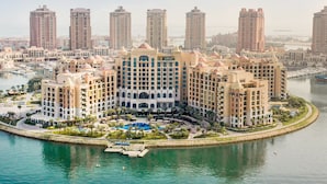 A high-rise hotel with multiple floors, a central courtyard, and a marina with boats. - The St. Regis Marsa Arabia Island, The Pearl Qatar (Doha)