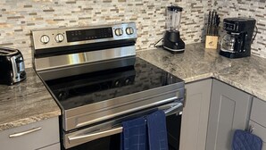 A modern kitchen with stainless steel appliances, a microwave, a stove, and a blender.