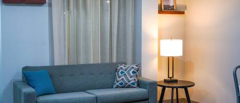 A living room with a grey sofa, a round coffee table, a lamp, and a chair.