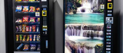 Two vending machines with snacks and beverages, one with a waterfall image.
