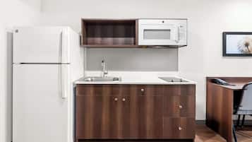A compact kitchen with a white refrigerator, a microwave, and a sink.
