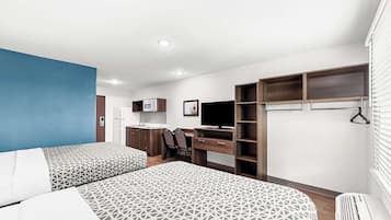 A modern hotel room with two beds, a desk, a TV, and built-in wardrobes.