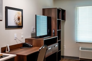 A hotel office with a desk, computer, phone, and framed picture on the wall.