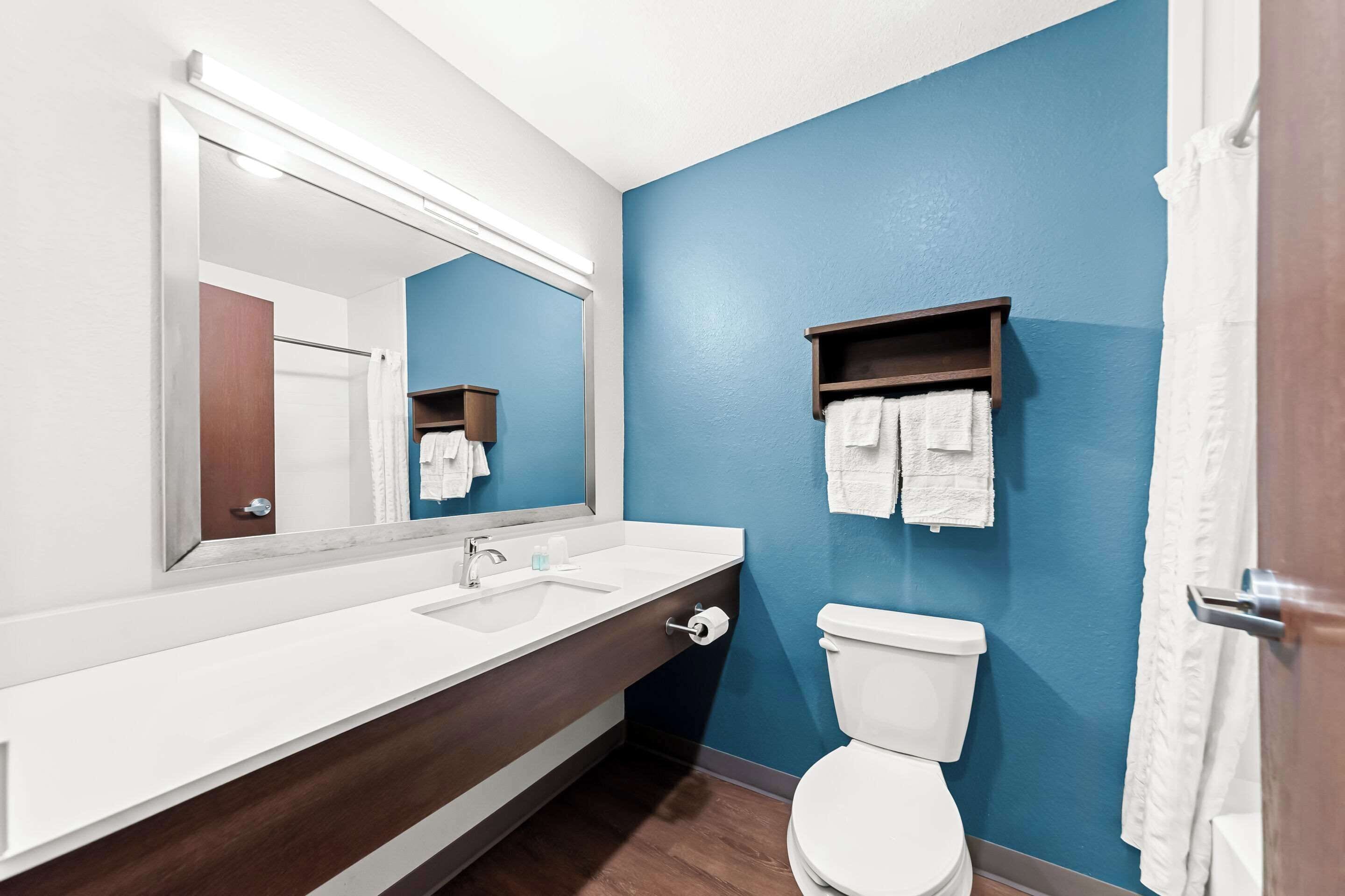 A bathroom with a white sink, a mirror, a toilet, and a towel rack.