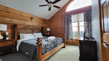 Une chambre aux murs lambrissés, dotée d’un lit à baldaquin, d’un ventilateur de plafond et d’une fenêtre avec des rideaux.