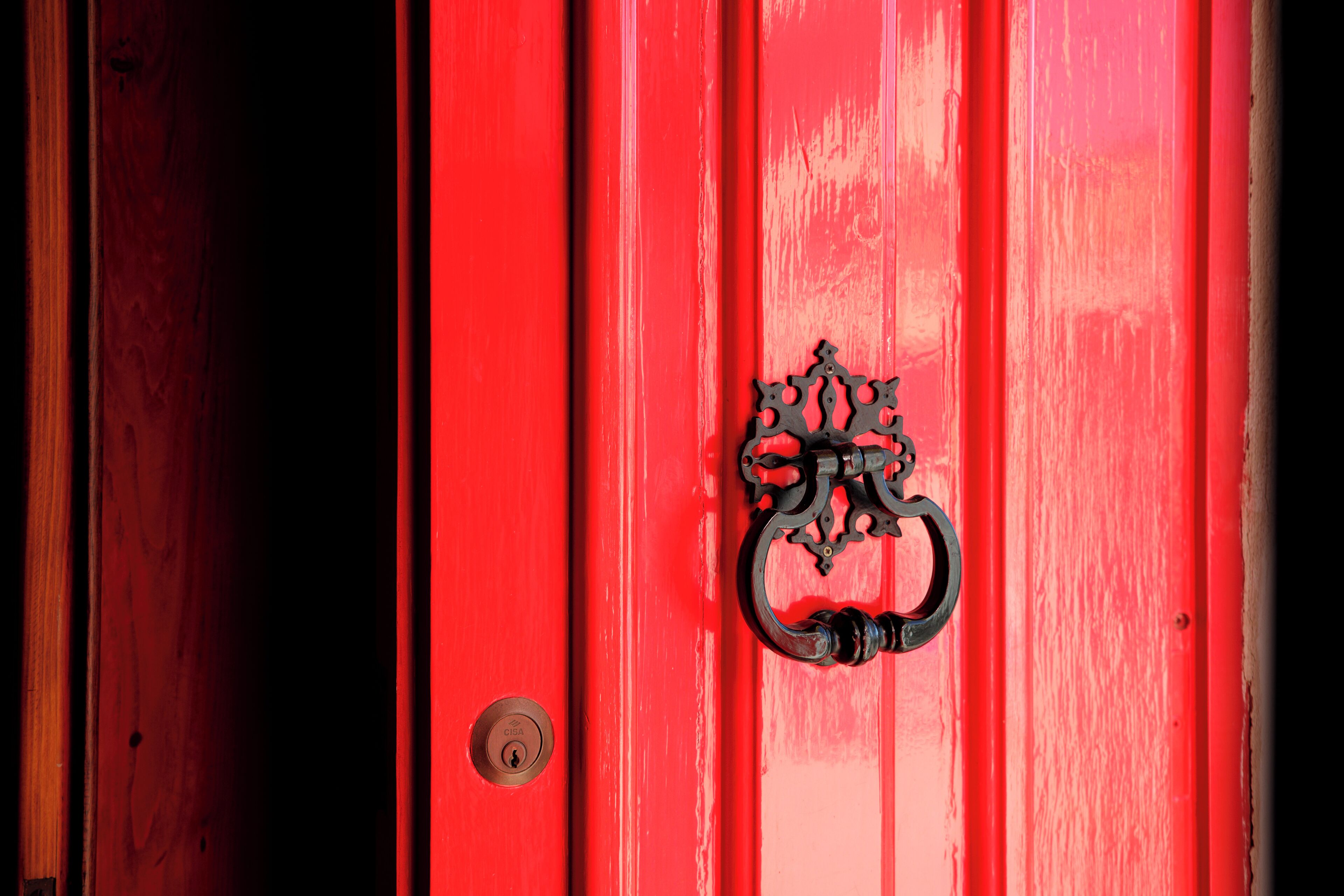 A red door with a metal handle and a keyhole.