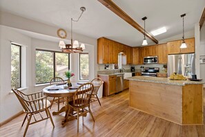 Una cocina amplia con armarios de madera, una isla central y un comedor con sillas de madera.