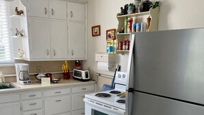 Une cuisine avec des armoires blanches, un réfrigérateur en acier inoxydable, une cuisinière et un four à micro-ondes.