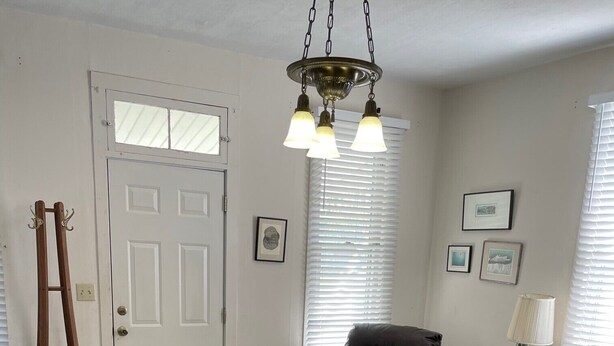 Un salon avec une échelle en bois, un fauteuil en cuir noir, un pouf marron et un canapé beige.