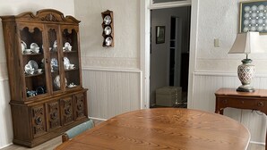 Une salle à manger avec une grande table en bois, des chaises, un buffet et une lampe.