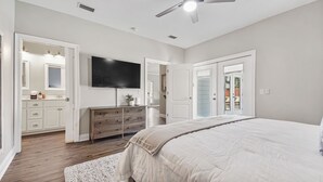 A bedroom with a bed, dresser, and TV. - Cozy home in a great location. Pool, ping-pong and arcade! (Panama City Beach)