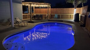 A swimming pool with a wooden deck and lounge chairs. - Cozy home in a great location. Pool, ping-pong and arcade! (Panama City Beach)