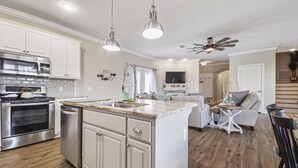 A modern kitchen with stainless steel appliances, a marble countertop, and pendant lighting. - Cozy home in a great location. Pool, ping-pong and arcade! (Panama City Beach)