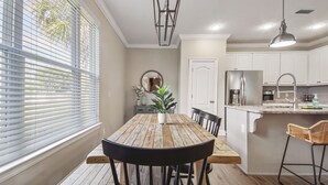 A dining area with a wooden table, chairs, and a potted plant. - Cozy home in a great location. Pool, ping-pong and arcade! (Panama City Beach)